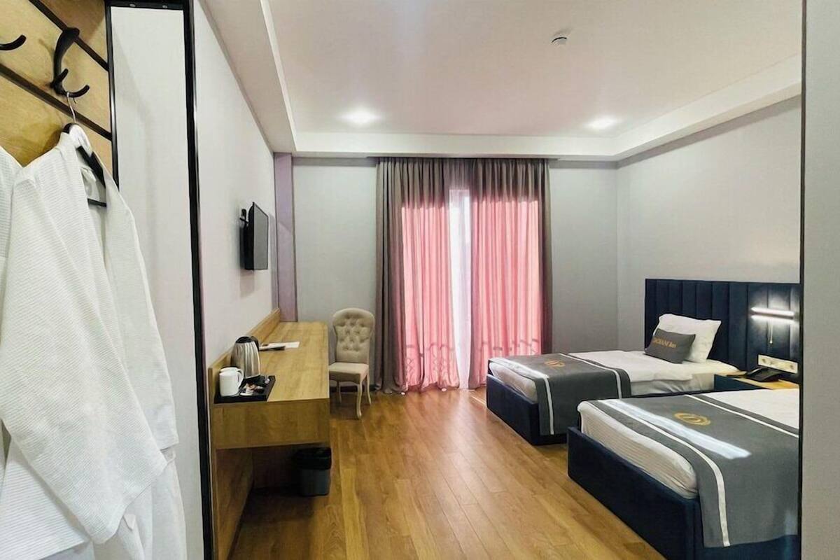 A hotel room with a bed, a desk, a chair, and a wardrobe.