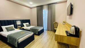 A hotel room with two beds, a desk, a chair, a TV, and a window with curtains. - DADIANI Inn (Zugdidi)