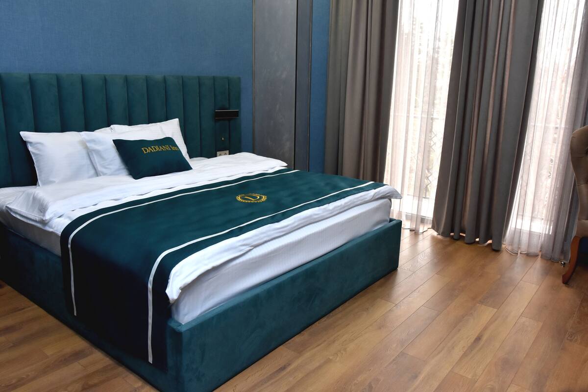 A neatly made bed with a green bedspread and white linens, a headboard, and a pillow with text.