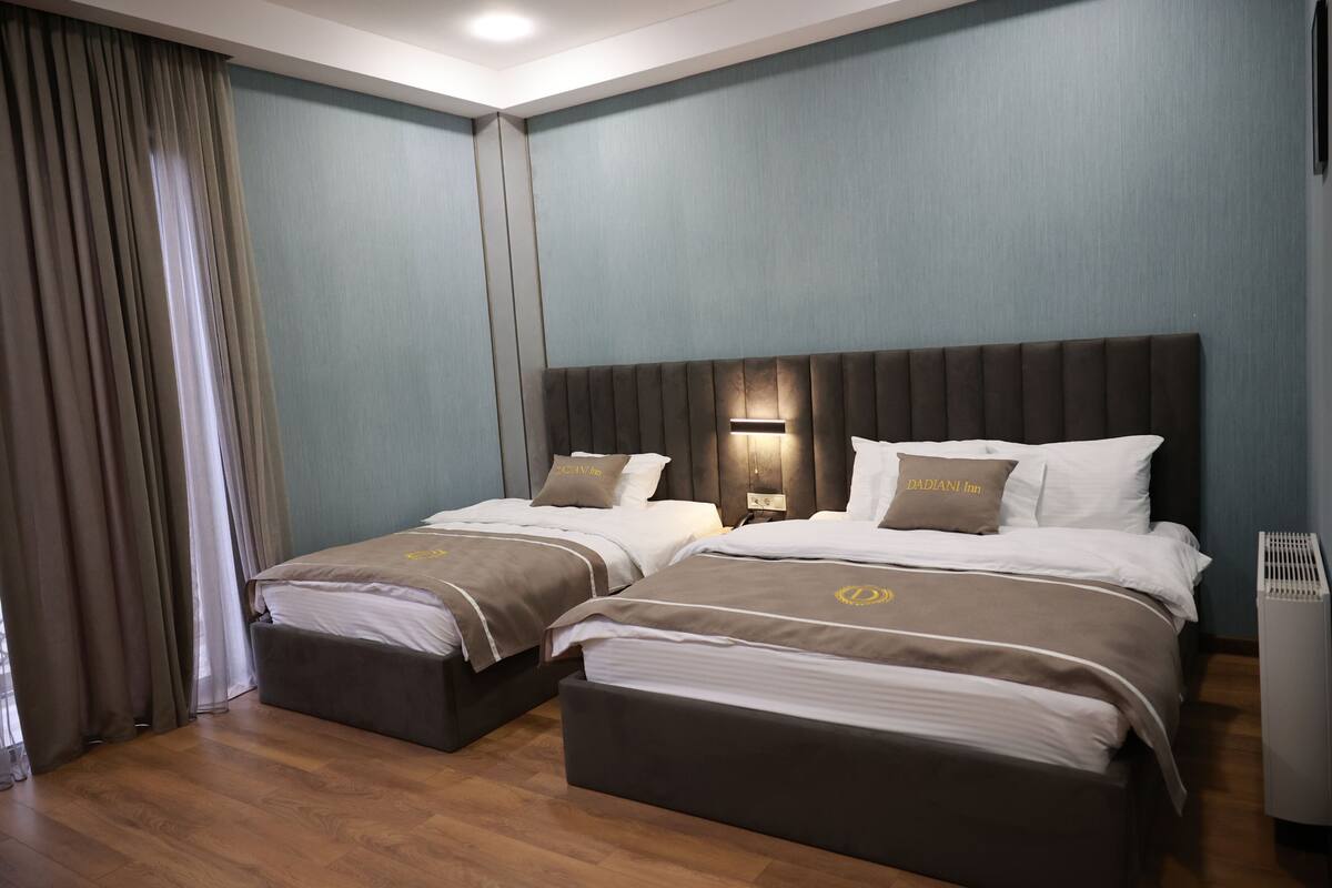 A hotel room with two beds, a large window with curtains, and a modern design.