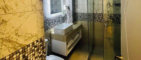 A modern bathroom with a glass shower, a white sink, and a toilet.