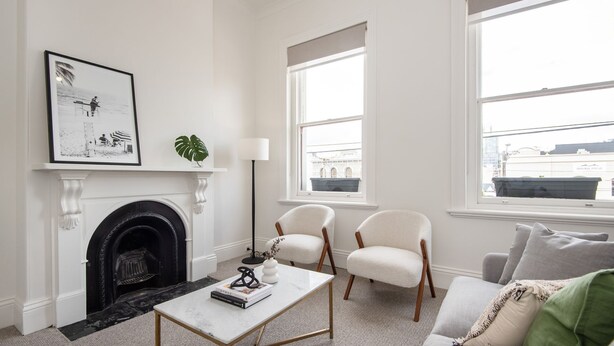 A living room with a fireplace, two armchairs, a sofa, a coffee table, and a framed picture on the wall. - Pet Friendly - Character and Charm on Emerald Hill (South Melbourne)