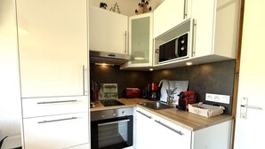 A compact kitchen with white cabinetry, a built-in oven, a microwave, and a coffee maker. - 2-room apartment in Praz Sur Arly, parking, close to slopes, for 5 people (Praz-sur-Arly)