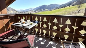 A balcony with a table set for two, overlooking a mountainous landscape. - 2-room apartment in Praz Sur Arly, parking, close to slopes, for 5 people (Praz-sur-Arly)