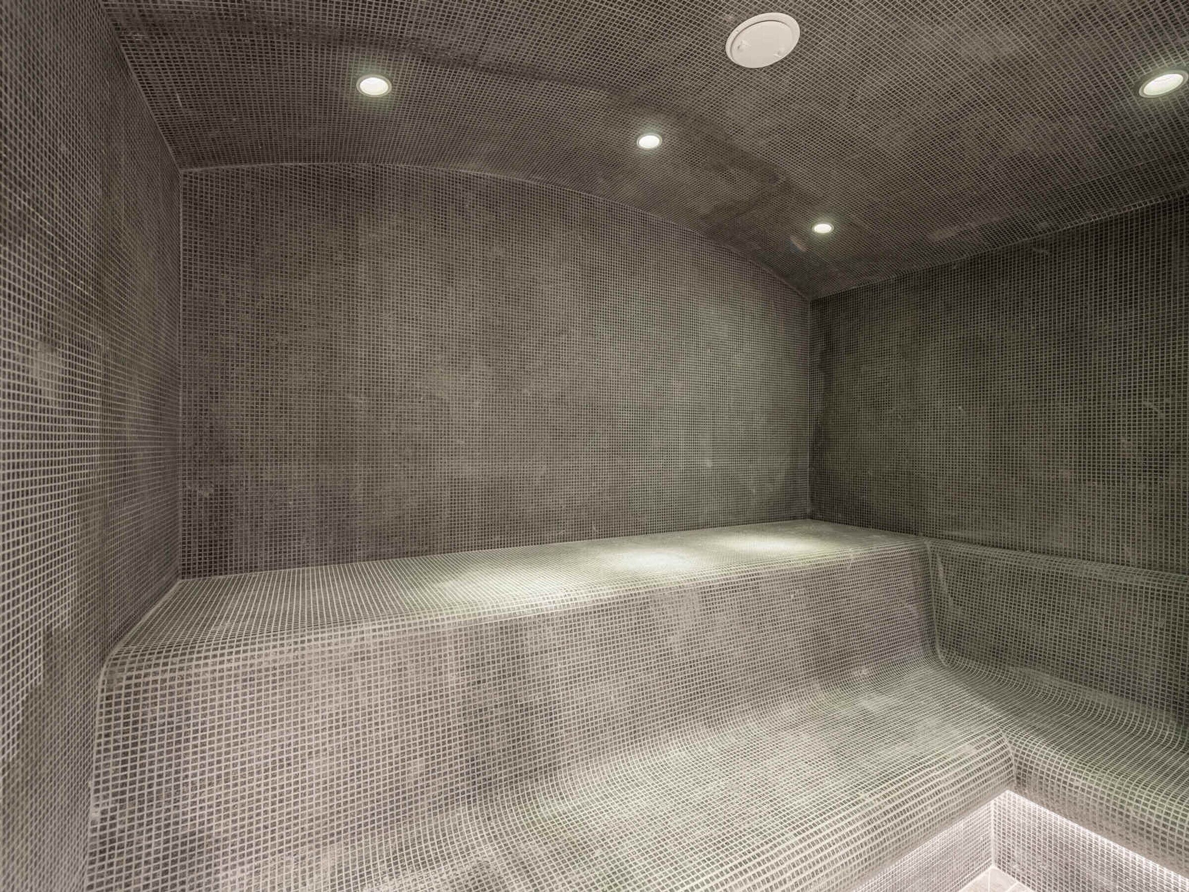 A room with a textured ceiling and walls, recessed lighting, and a bench-like seating area.