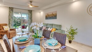 Una sala de estar moderna con comedor, que incluye un sofá, una mesa de centro y una mesa de comedor con platos y vasos.