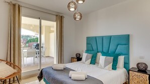Un dormitorio con una cama grande, vistas al exterior y un comedor visible a través del ventanal.