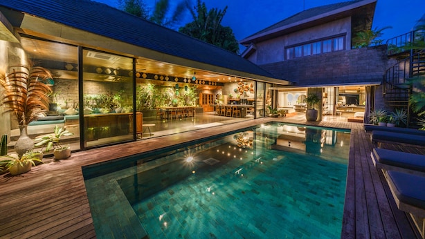 A modern house with a swimming pool, large windows, and a wooden deck. - Love Supreme Villa by Betterplace (Canggu)