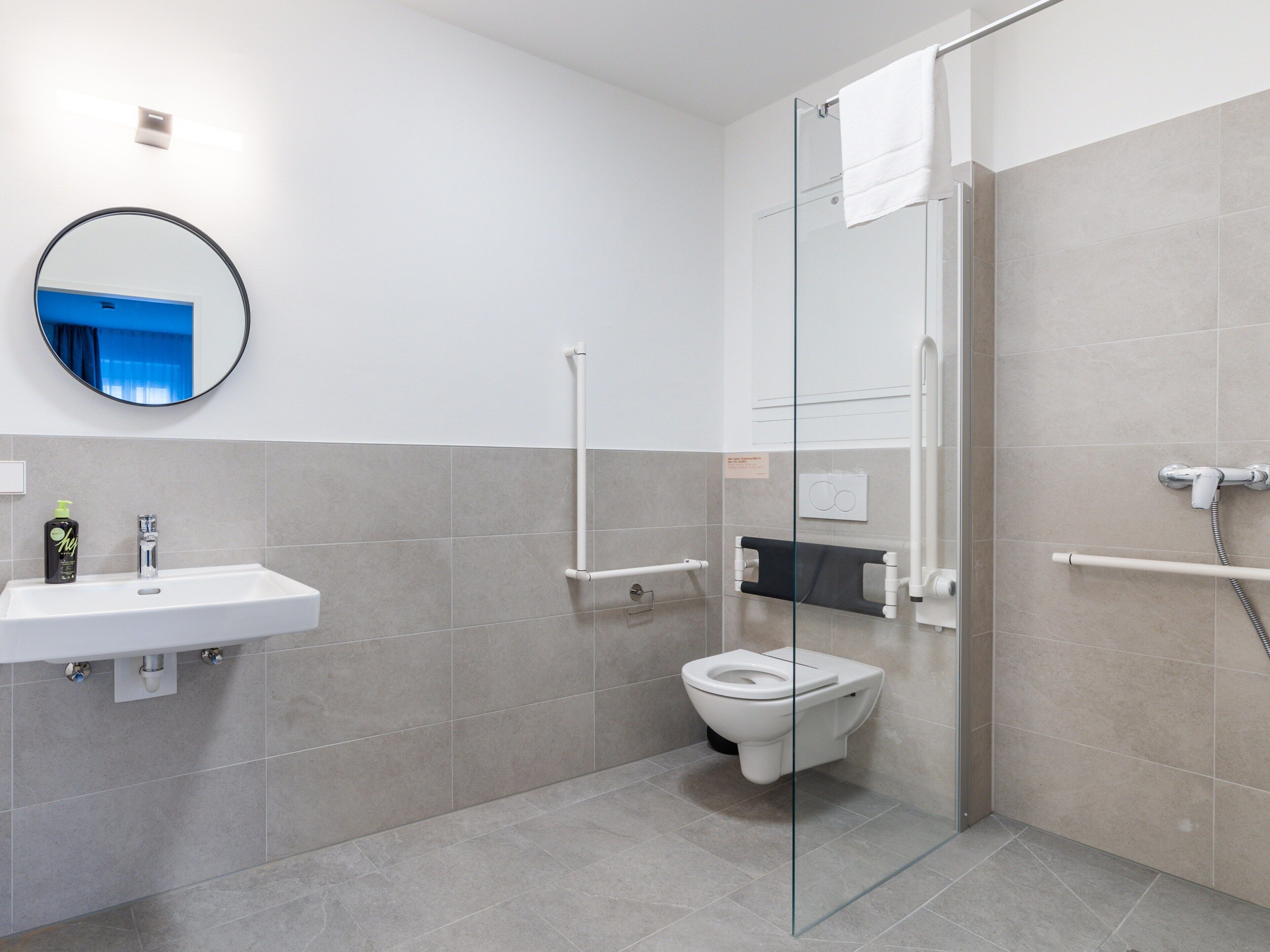 Un baño moderno con cabina de ducha de vidrio, un lavamanos blanco y un inodoro.
