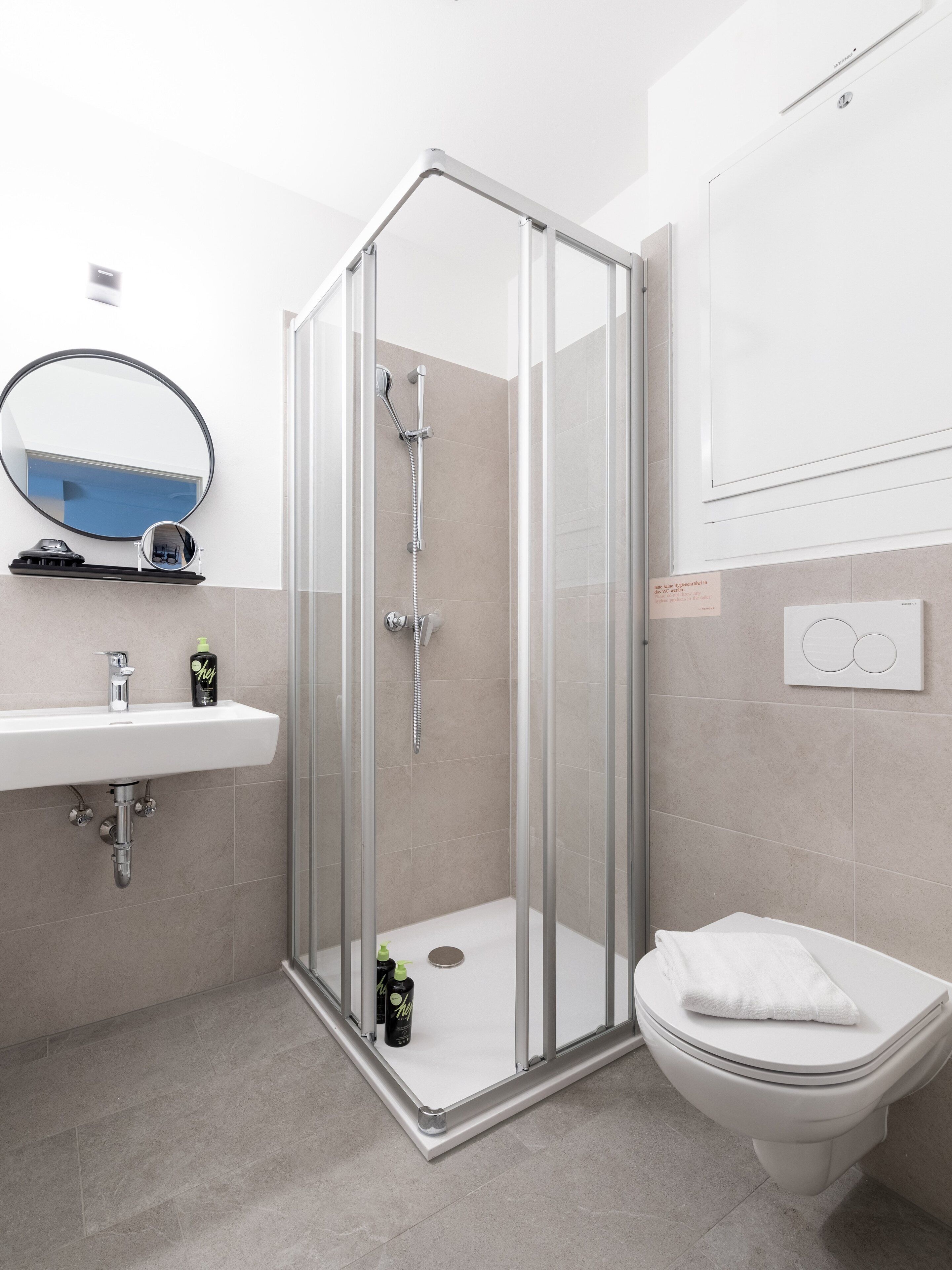 A modern bathroom with a glass-enclosed shower, a white sink, and a toilet.