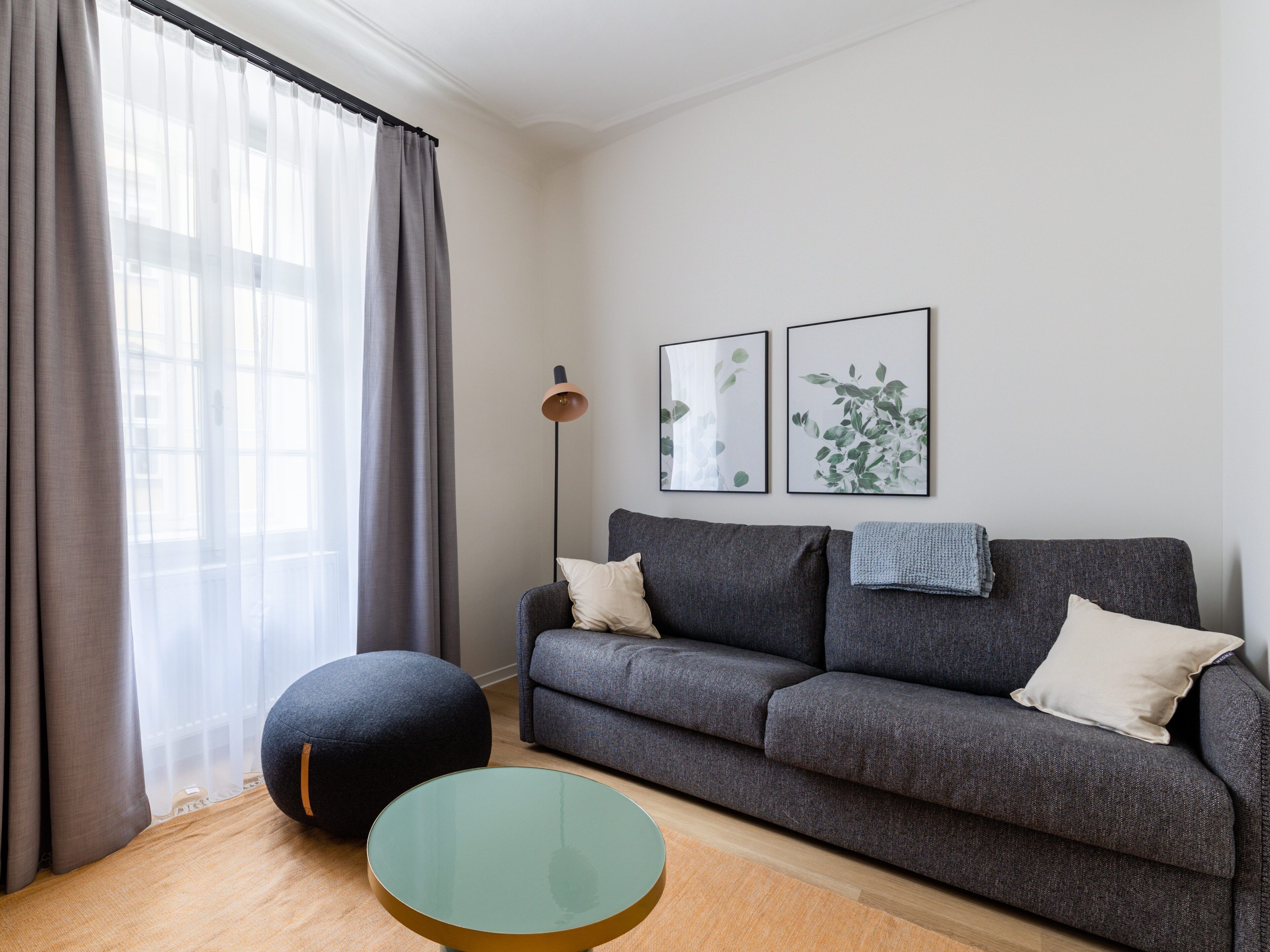 A modern living room with a grey sofa, a round glass coffee table, and a floor lamp.