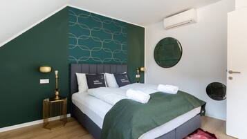A modern bedroom with a bed, green walls, and a decorative wall panel.
