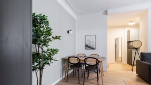 Un espace repas moderne avec une table et des chaises en bois, une plante en pot et un tableau encadré au mur.