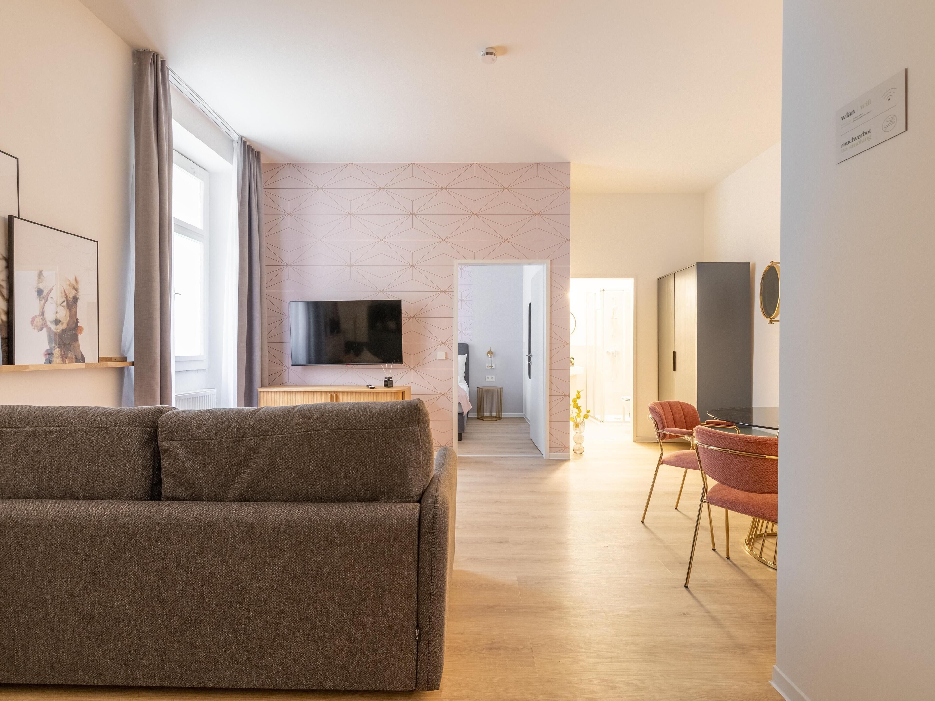 A modern living room with a sofa, a flat-screen TV, and a dining area with a chair.