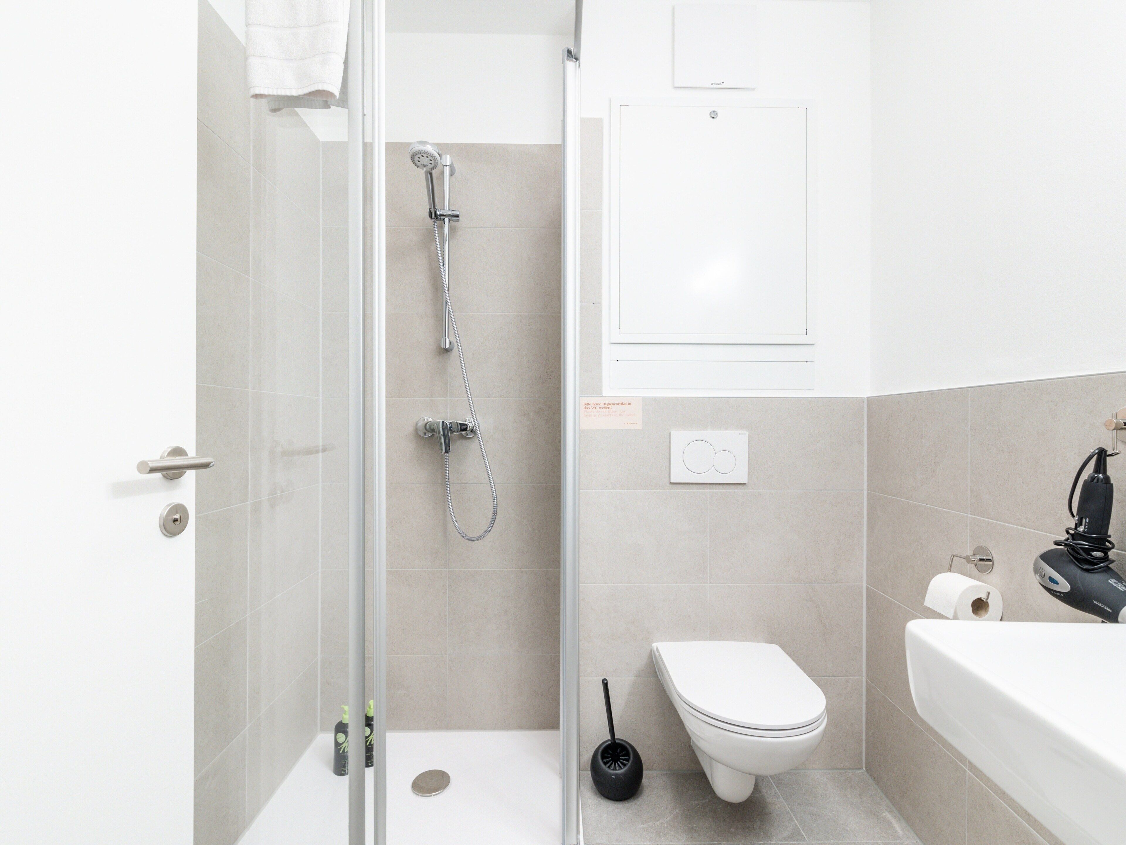 A modern bathroom with a shower, toilet, and sink.