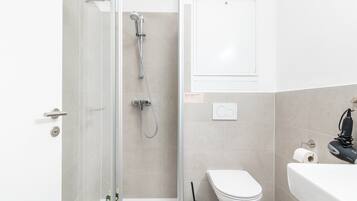 A modern bathroom with a shower, toilet, and sink.
