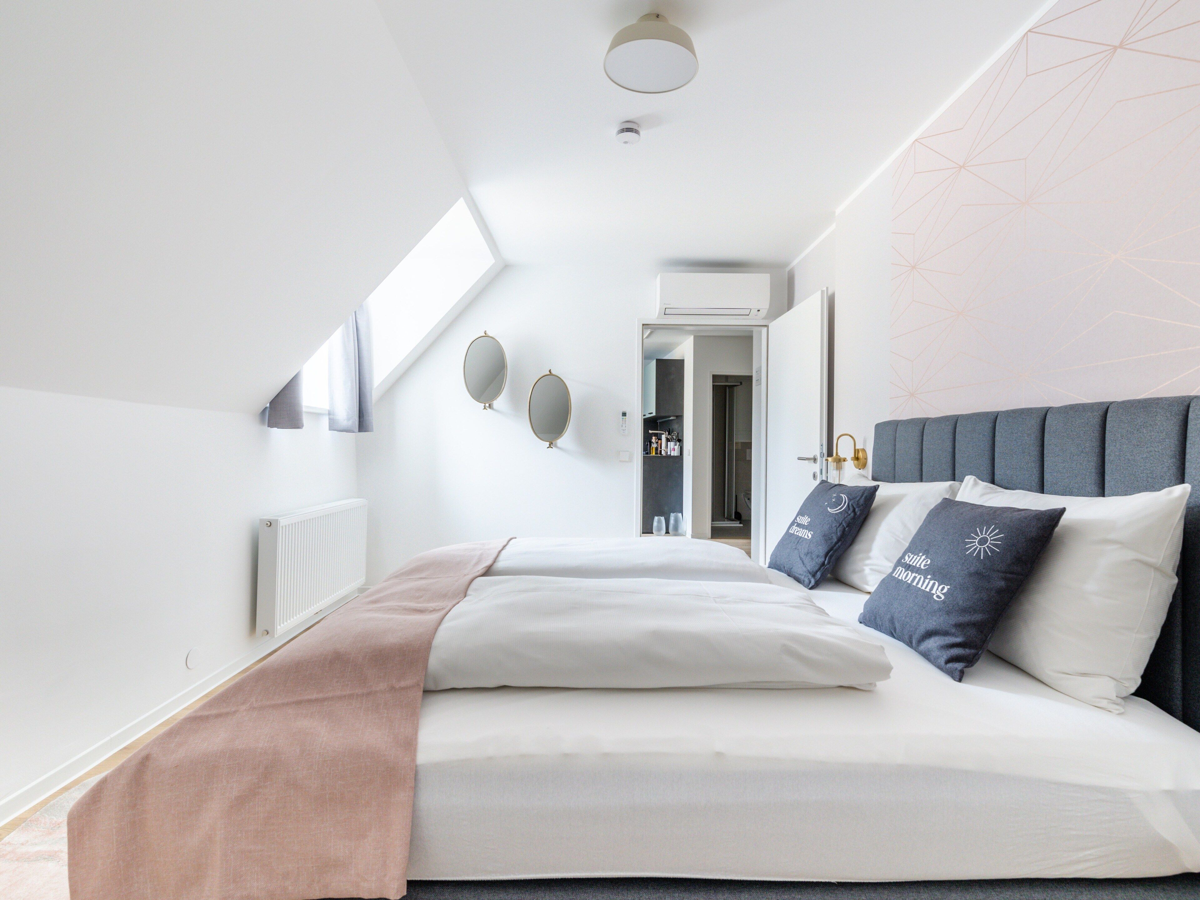 Un dormitorio moderno con una cama grande, un cabecero y un tragaluz.