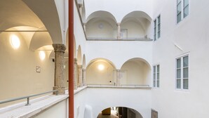 Un intérieur à plusieurs niveaux, avec des couloirs en arc de cercle et une colonne centrale, comprenant un escalier et offrant une vue sur un niveau inférieur.