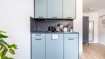 Uma cozinha moderna com armários azul-claros, bancada preta e uma pequena planta no canto.