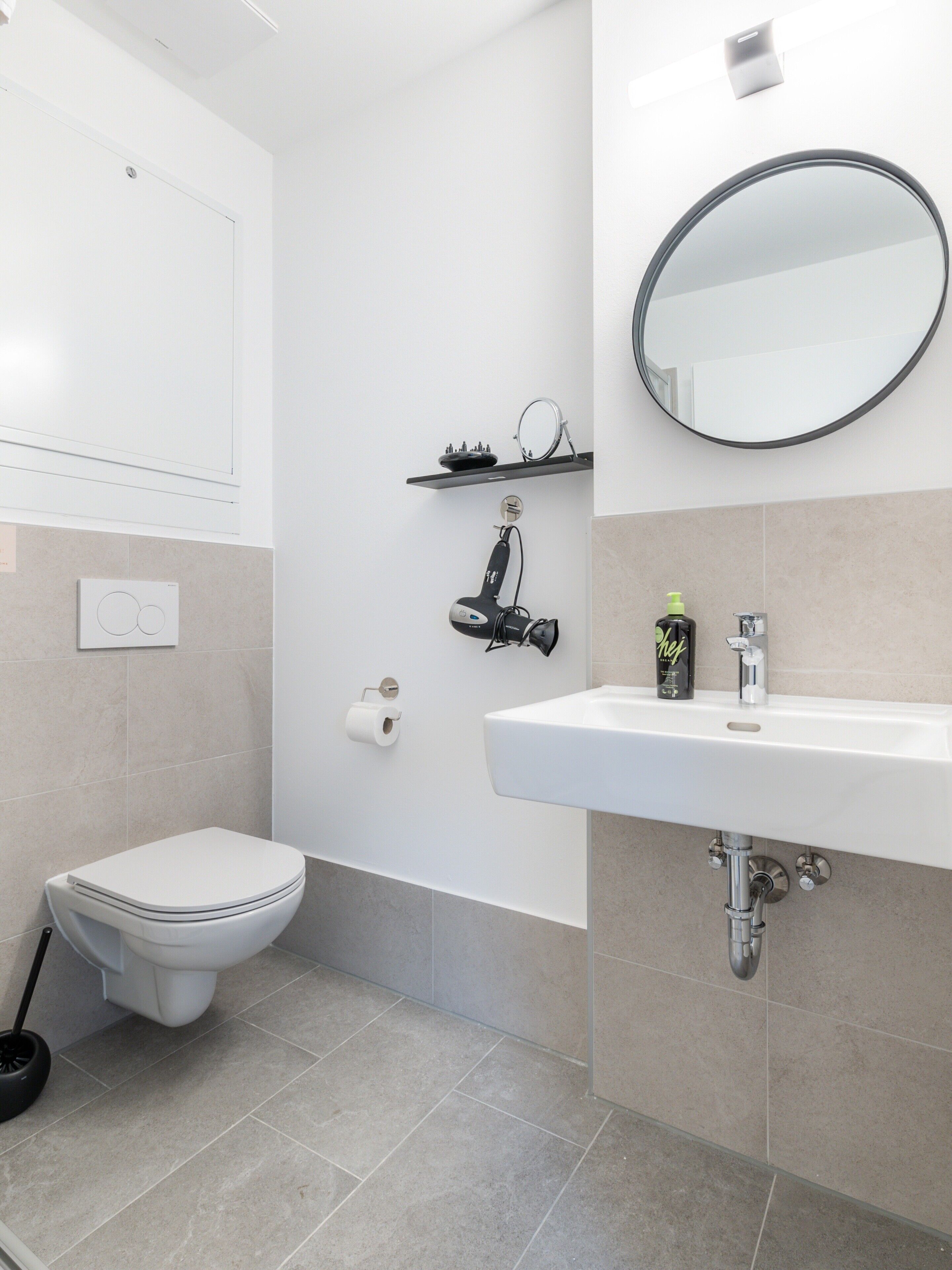 A modern bathroom with a toilet, sink, and mirror.