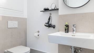 A modern bathroom with a toilet, sink, and mirror.