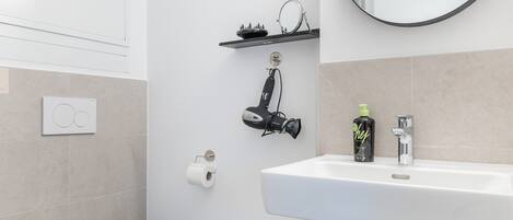 A modern bathroom with a toilet, sink, and mirror.