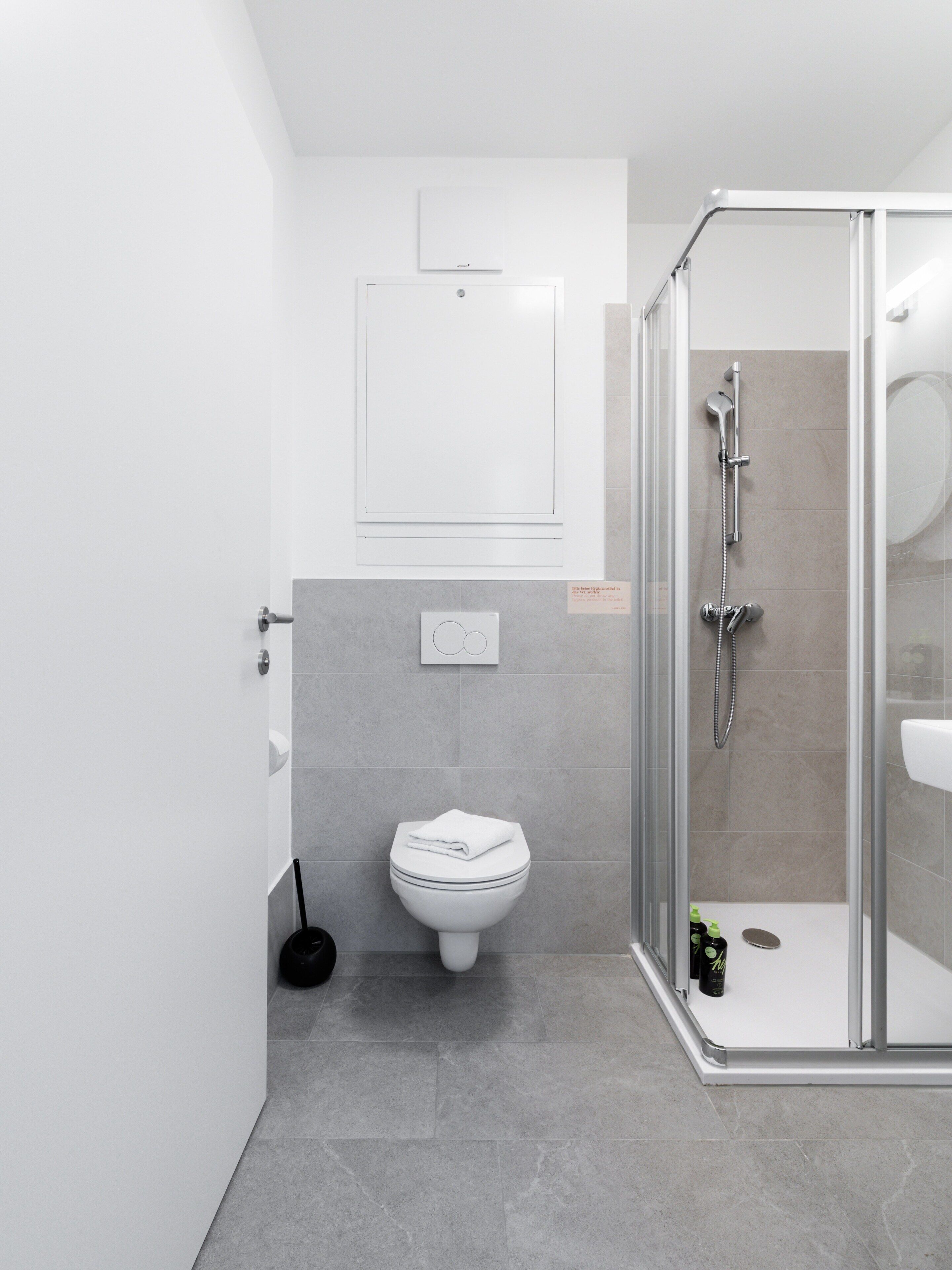 Ein modernes Badezimmer mit Toilette, Dusche und einer gläsernen Duschkabine.
