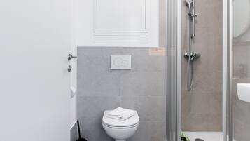 Ein modernes Badezimmer mit Toilette, Dusche und einer gläsernen Duschkabine.
