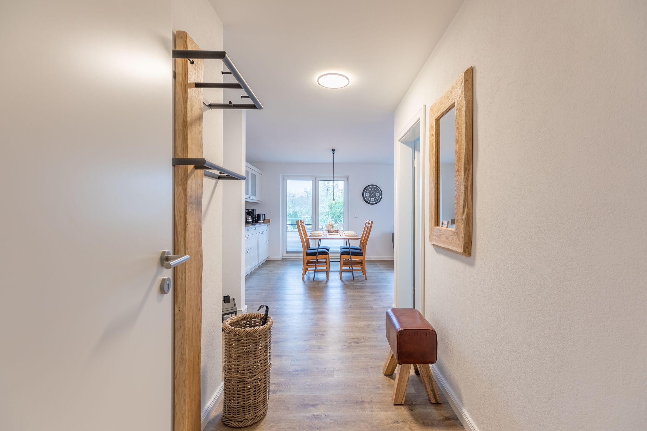 A hallway leading to a dining area with a table and chairs, a wicker basket, and a bench.