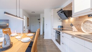 A modern kitchen with white cabinetry, a wooden countertop, and a built-in oven. - The Emma vacation apartment in St. Peter-Dorf for up to 4 people (St. Peter-Dorf)