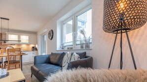 A modern living room with a sofa, a dining table, and a lamp. - The Emma vacation apartment in St. Peter-Dorf for up to 4 people (St. Peter-Dorf)