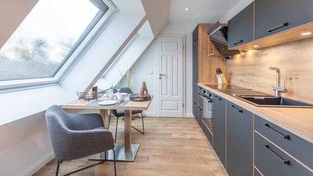 Eine moderne Küche mit Oberlicht, Holzausstattung und einem Essbereich mit Tisch und Stühlen.