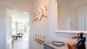 Un passadís amb una mànega per abrigalls, un plat de sabó amb forma de pato i vista a una habitació amb una cadira i una taula.