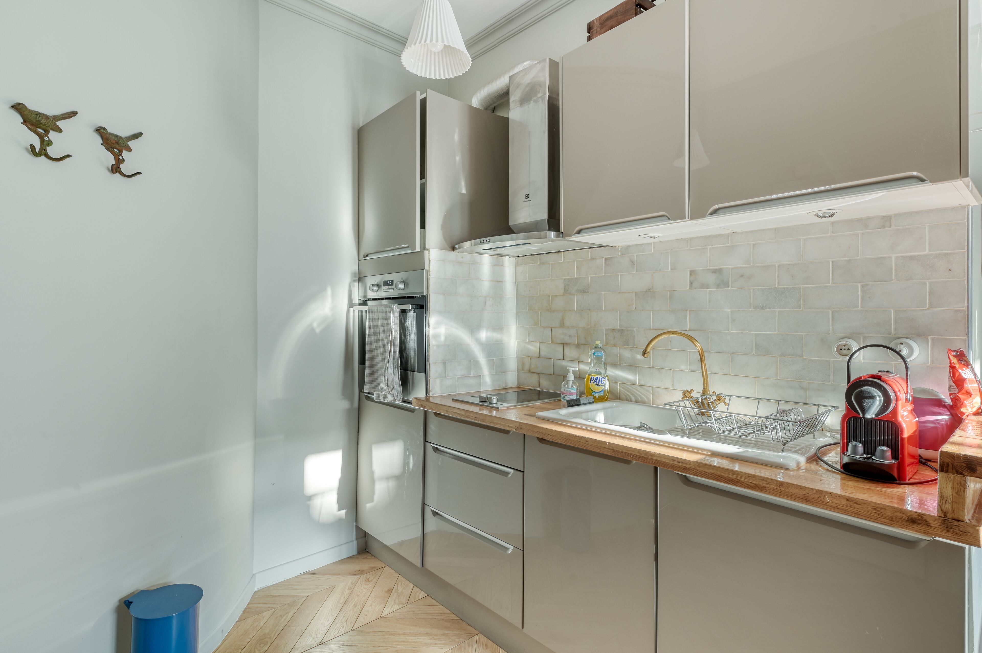 A modern kitchen with stainless steel appliances, a wooden countertop, and a tiled backsplash.