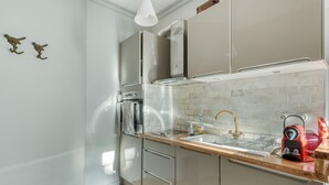 Una cocina moderna con electrodomésticos de acero inoxidable, encimera de madera y salpicadero de azulejos.