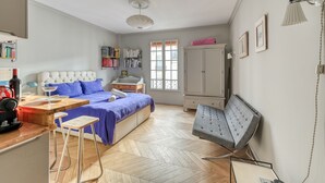 Un dormitorio con cama, escritorio, silla, armario y ventana.