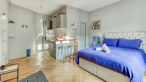 Un dormitorio moderno con una cama grande, un escritorio empotrado y una kitchenette.