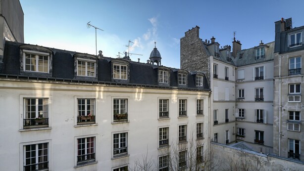 Un edificio de varios pisos con fachada blanca, numerosas ventanas y balcones.