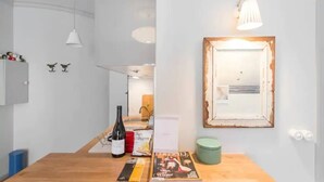 Una habitación con una mesa de madera, una botella de vino, una revista y un cuadro en la pared.