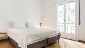 Ein Schlafzimmer mit einem Bett, einem Nachttisch und einem Fenster mit Blick auf Grünflächen.