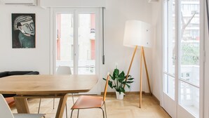 Ein modernes Zimmer mit einem Holztisch, zwei Stühlen, einer Stehlampe und einem Blumentopf.