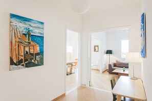 A modern living room with a painting of a boat on the wall, a sofa, a coffee table, and a lamp.