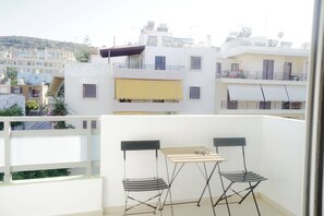 En balkon med et bord og stole, der giver udsigt over et boligområde med flere bygninger.