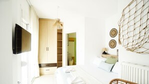 Een slaapkamer met een bed, een televisie, een kledingkast en een rieten stoel.
