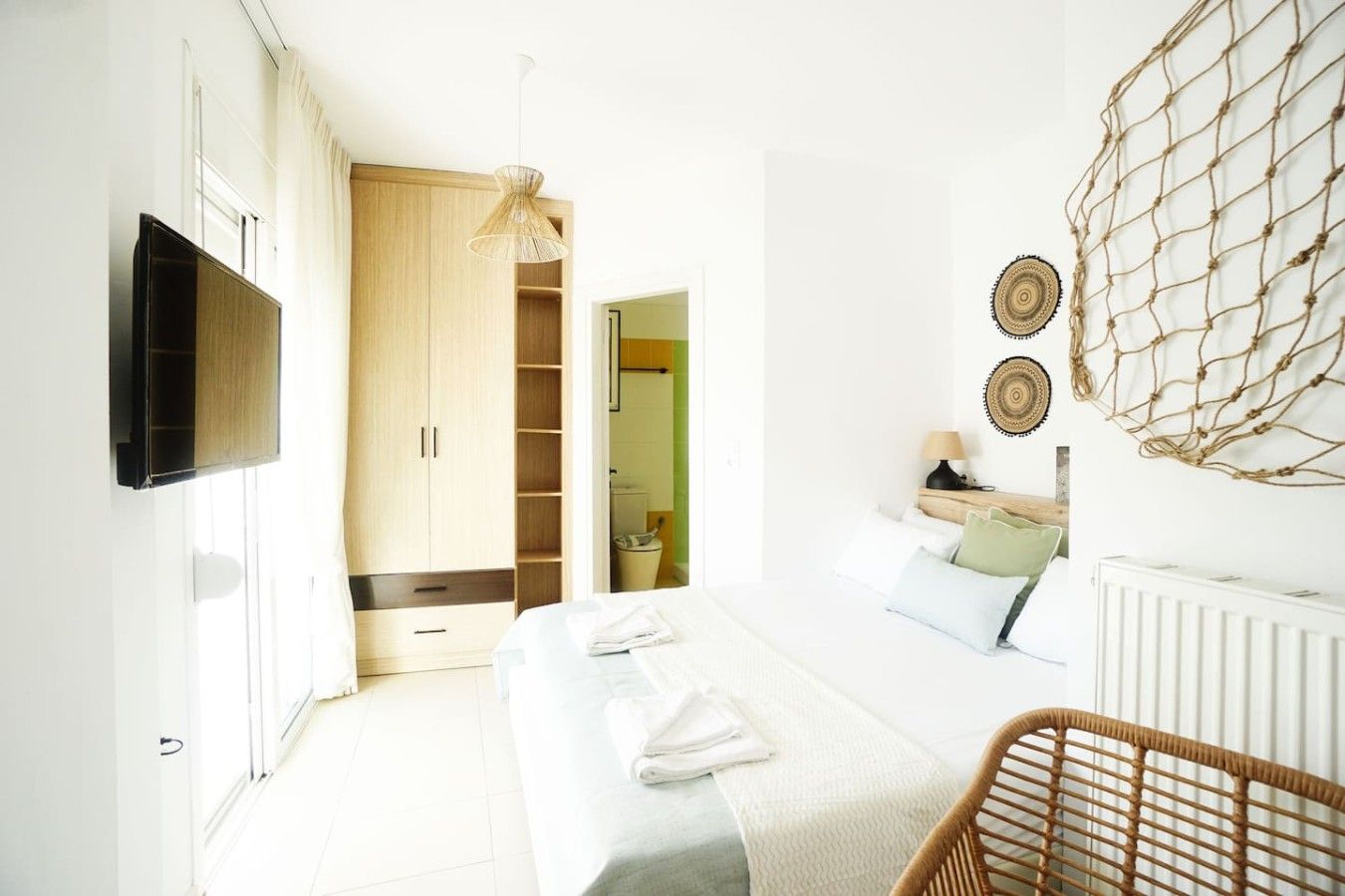 Een slaapkamer met een bed, een televisie, een kledingkast en een stoel.
