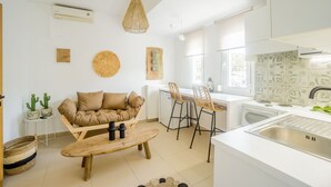 Een moderne keuken met witte kasten, een houten eettafel en een barkruk.