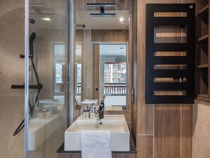 A modern bathroom with a glass shower enclosure, a large mirror, and a wooden vanity.