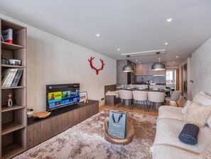 Una sala de estar moderna con un televisor de pantalla plana, un mueble de madera para entretenimiento, una alfombra mullida y un sofá.