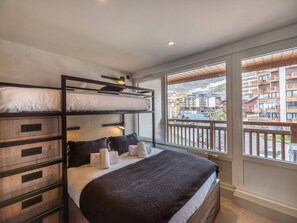 Een slaapkamer met stapelbedden en uitzicht op een berg en gebouwen.