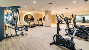 A modern gym with various cardio machines, weight training equipment, and a spacious layout.